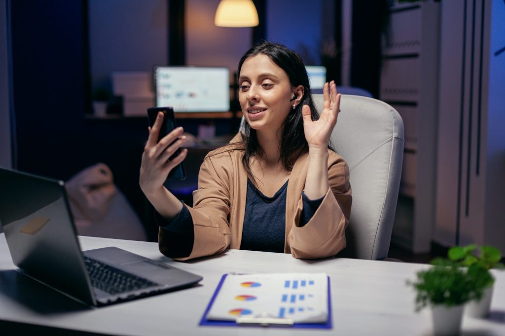 Businesswoman waving in the course of call with colleagues