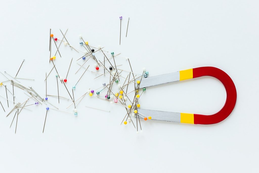 Overhead shot of a colorful magnet and a pile of pins and needles attached to it